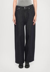 Σκούρες μπλε φαρδιές τζιν παντελόνες με πέντε τσέπες, ασημένια αξεσουάρ και ψηλή μέση. Κατασκευασμένες από τζιν με λεία υφή.