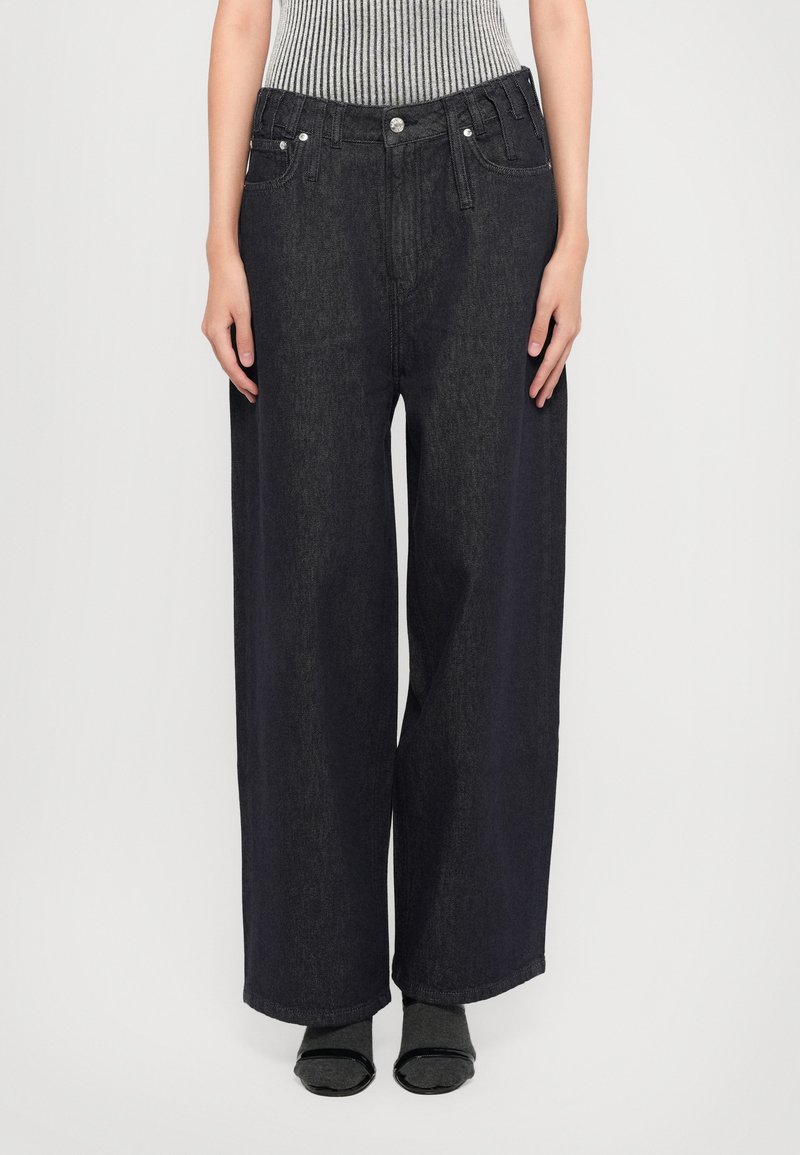 Σκούρες μπλε φαρδιές τζιν παντελόνες με πέντε τσέπες, ασημένια αξεσουάρ και ψηλή μέση. Κατασκευασμένες από τζιν με λεία υφή.