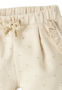 Hosen aus einer Baumwollmischung in Cremefarbe mit kleinen, tanfarbenen Punkten. Mit einem elastischen Bund und Rüschendetails an den Seitentaschen.