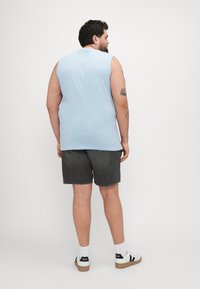 Chemise sans manches bleu clair, shorts en denim noir, baskets blanches avec accents noirs, en matériau coton, et coupe décontractée.