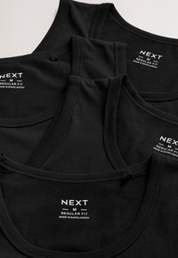 Quatre débardeurs noirs de taille moyenne, étiquetés « NEXT M Regular Fit Made in Bangladesh », empilés sur un fond clair.