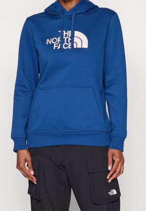 Blauwe hoodie van zachte stof met een buidelzak, voorzien van een lichtgekleurde logo van "The North Face" op de borst.