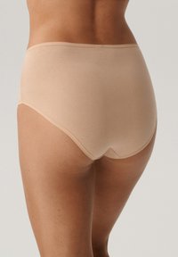 Beżowa bielizna wysoka z gładkiego materiału, charakteryzująca się bezszwowym krojem, niskim dekoltem na plecach i elastycznym pasem.