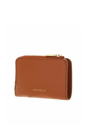 Portefeuille en cuir marron avec fermeture éclair à tirette dorée et logo "COCCINELLE" embossé en doré au centre devant.