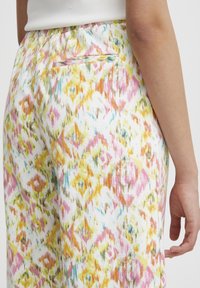 Kleurige, gebloemde broeken van lichtgewicht stof; kenmerken roze, gele en blauwe tinten met een achterzak en een elastische taille.