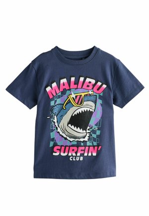 T-shirt en coton bleu marine avec un graphisme de requin portant des lunettes de soleil, avec "MALIBU SURFIN' CLUB" imprimé en gras en rose et blanc.