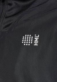 Sort atletisk jakke med et tekstureret stof og lynlås. Bemærkelsesværdig hvid logo design inkluderer prikker og mærkenavnet "HML."
