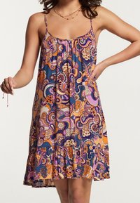 Robe sans manches longueur genou, motif cachemire en bleu marine, orange et rose, avec un corsage froncé et un ourlet à volants. Tissu léger.