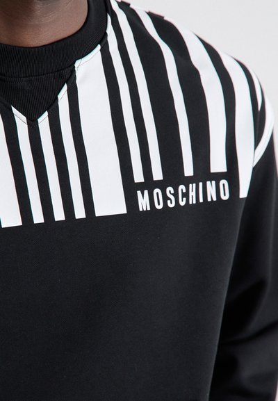 Sweatshirt preto com riscas brancas verticais e o logótipo "Moschino". O tecido tem uma textura suave, com um detalhe de gola canelada.