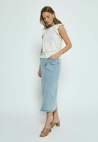 Witte top met geruffelde mouwen, gecombineerd met een lichtblauwe denimrok en tankleurige blokhak-sandalen. Eenvoudige, casual stijl met een ontspannen pasvorm.