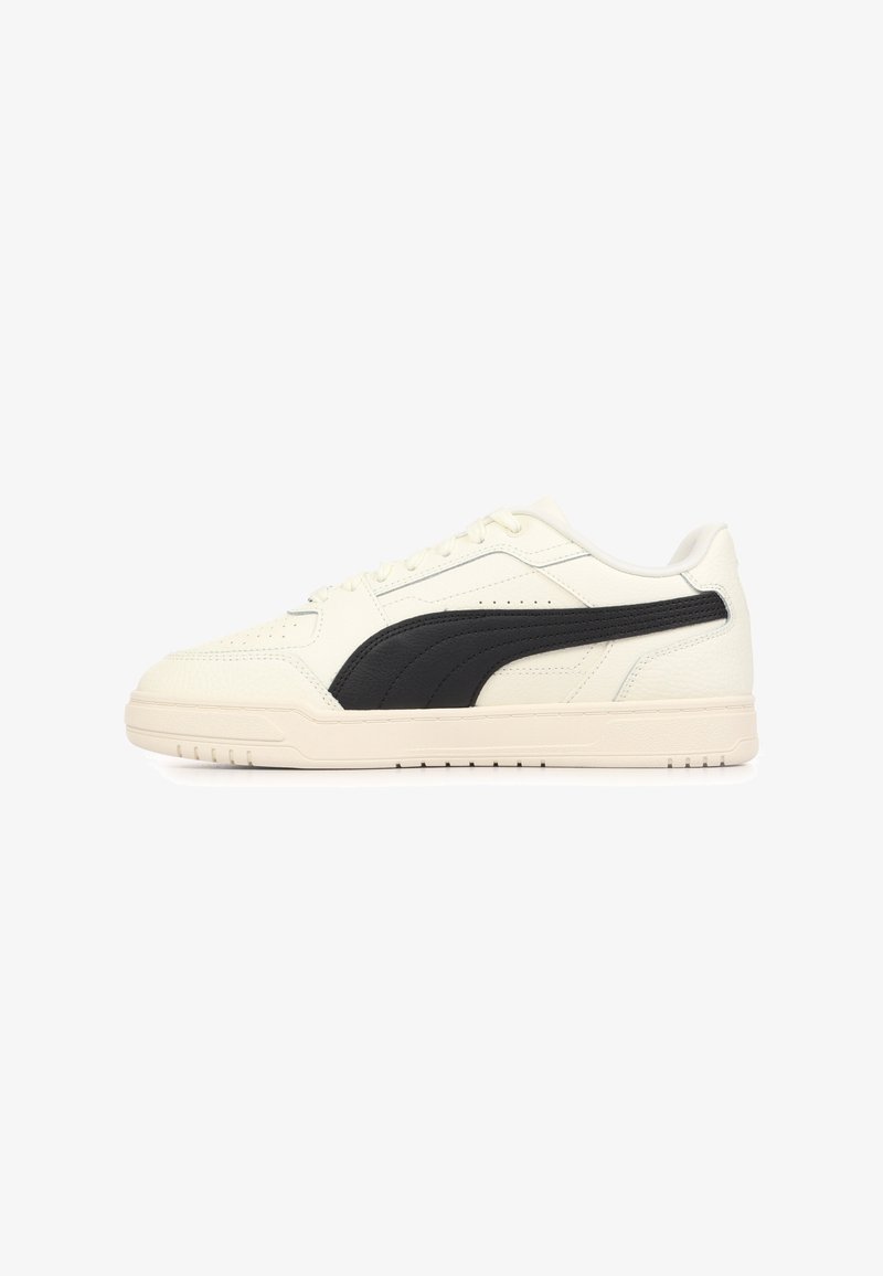 Baskets en cuir blanc avec un logo PUMA noir, design bas, dessus texturé, fermeture à lacets à l'avant et semelle extérieure en caoutchouc présentant des motifs antidérapants.