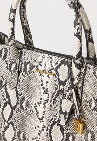 Sac fourre-tout imprimé serpent en noir et blanc ; présente un extérieur texturé, du matériel doré et un charme détachable avec logo.