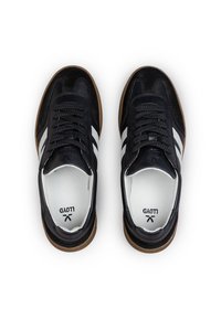 Coppia di sneakers nere con strisce laterali bianche, lacci neri, suole in gomma e solette bianche con logo nero, viste dall'alto.