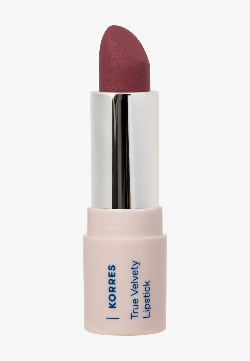Matte mauve huulipuna hopeisessa putkessa ja vaaleanpunaisessa pohjassa, jossa lukee "Korres True Velvety Lipstick", valkoista taustaa vasten.