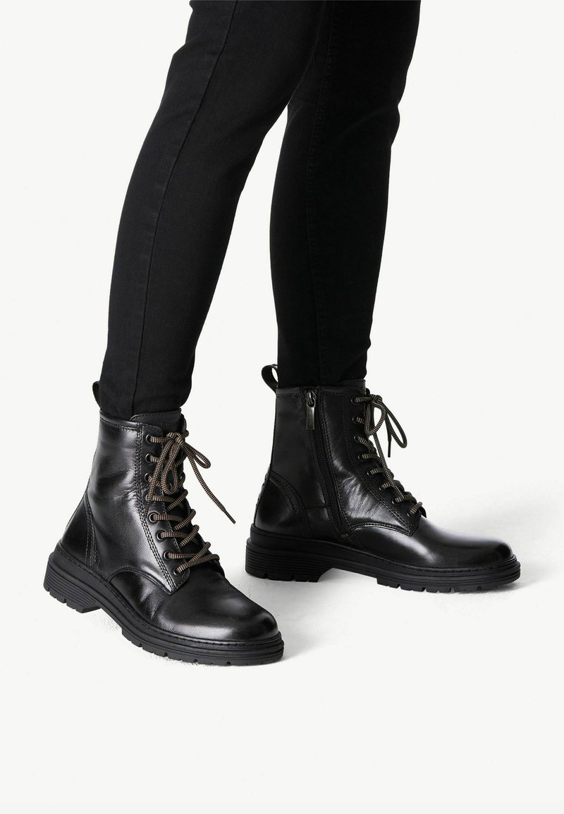 Des bottes de combat en cuir noir présentent un laçage à l'avant, une fermeture éclair sur le côté, un bout rond, une semelle texturée et des lacets assortis, conçues pour la durabilité et le confort.