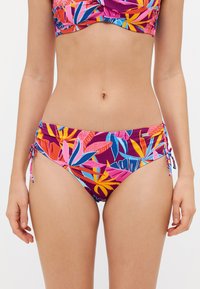 Spalvingas bikinis, kurio pagrindas yra purpurinės spalvos, su ryškiomis tropinėmis lapų raštais rožinės, mėlynos ir geltonos spalvų. Šoninės rišamosios detalės suteikia galimybę reguliuoti dydį.