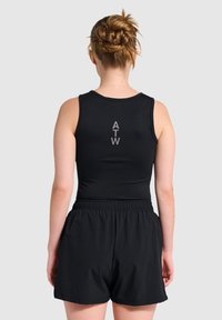 Zwarte sportieve tanktop met een ronde hals en het logo "ATW" verticaal op de achterkant gedrukt, gecombineerd met zwarte shorts met een elastische taille.