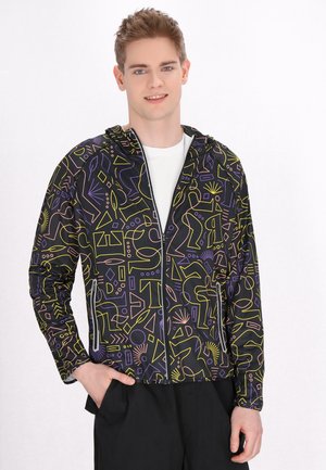 Zwarte jas met kleurrijke geometrische patronen in geel, roze en paars. Voorzien van een ritssluitingen en een capuchon. Ideaal voor casual kleding.