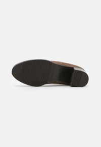 Hnědé semišové boty s černou gumovou podrážkou, vybavené horizontálními drážkami pro lepší přilnavost. Design je minimalistický, bez výrazných akcentů.