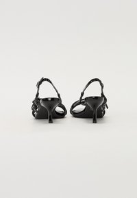 Sorte hælede sandaler med åben bag, der har en stribet design, glansfuld finish og slanke hæle. Glat tekstur med minimale hardware accenter.