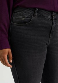 Svarta denimjeans med slim fit, som har subtila blekningar, en knapp- och dragkedja, samt en framficka med ljusa sömnadsdetaljer.