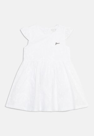 Robe blanche pour bébé avec manches courtes à volants, taille froncée, motif floral subtil et petit logo « Guess » sur la poitrine.