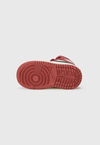 Crvena sneakerska potplat s uzorčenim gaznim slojem, zaobljenim nožnim prstom i bočnim detaljima. Materijal izgleda kao guma s teksturiranom završnom obradom.