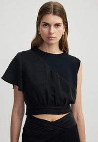 Zwart cropped top met asymmetrisch ontwerp met één schouder, gladde textuur en geplooide taille-details; mouwloos met een gestructureerde pasvorm.