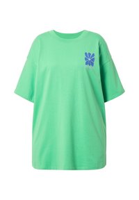 Tyrkysové oversized tričko vyrobené z bavlny. Má krátké rukávy a modrou květinovou grafiku na levé části hrudi.