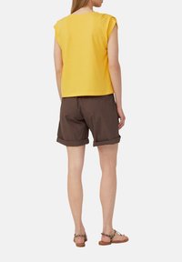 Yellow short-sleeve top paired with brown cuffed shorts. The shorts have a smooth texture and the top has a relaxed fit and soft fabric.