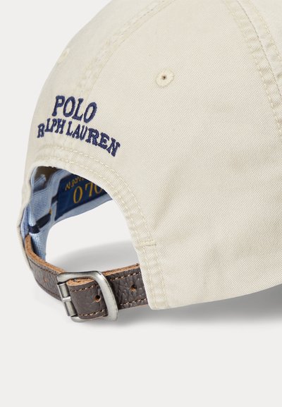 Bež bombažna kapa z vezenim "POLO RALPH LAUREN" v mornarsko modri barvi, nastavljivim rjavim usnjenim trakom z kovinsko sponko.