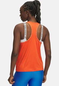 Oranje sporttanktop met een racerback ontwerp, voorzien van witte accenten en verstelbare bandjes. De stof lijkt soepel en lichtgewicht.