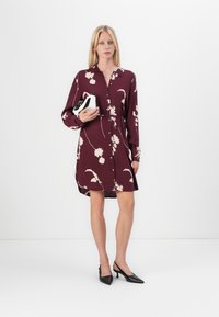 Maroone suknelė su ilgu rankovėmis, gėlių raštas kreminės spalvos, juosmens raištelis, virš kelių ilgio, poruojama su juodais slingback aukštakulniais.