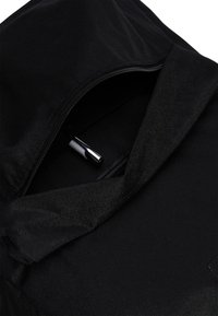 Svart ryggsäck med dragkedja och ett slätt, texturerat tyg. Innehåller en silverpenna synlig inne i huvudfacket.