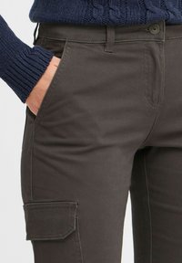 Mørkegrå cargo-bukser med en glat tekstur, der har sidelommer og knaplukning, parret med en navy strikket sweater med manchetter.