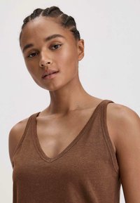 Bruine v-hals tanktop van zachte stof, met dunne schouderbandjes en een slim fit. Glad oppervlak met een subtiele glans.