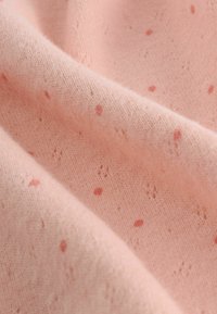 Helles pinkes Gewebe mit einer weichen Textur, das über kleine dunkelrosa Sprenkler und ein dezentes Strickmuster verfügt.