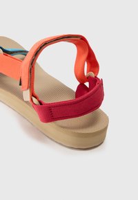Multicolored sandals featuring orange and red straps, a textured beige footbed, and a light tan, slightly elevated sole.