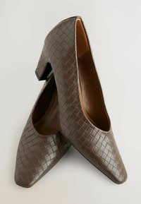 Brown high-heeled shoes featuring a woven texture, pointed toe, and a block heel, with a smooth interior.