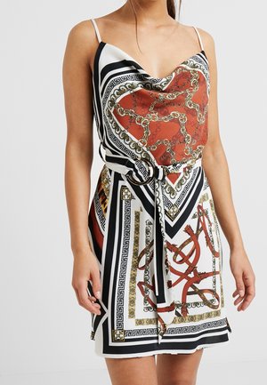 Saténové mini šaty s tenkými ramínky, zdobené vzorem červených a zlatých řetězů na bílém a černém geometrickém pozadí. Obsahují pás k zavázání v pase.