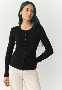 Schwarze gerippte Strickjacke mit Rundhalsausschnitt, langen Ärmeln und Knopfverschluss vorne. Hat eine enganliegende Silhouette und eine glatte Textur.