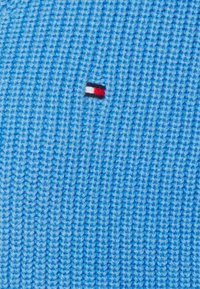 Niebieska dzianina z małym haftowanym logo, składającym się z czerwonych, białych i czarnych sekcji, umieszczonym centralnie.