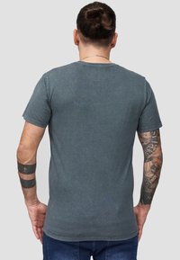 Harmaa, istuva crew neck -t-paita, joka on valmistettu puuvillasta. Paidassa on lyhyet hihat ja yksinkertainen selkäosa, jossa ei ole näkyviä grafiikoita tai kuvioita.