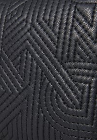 Svart läderprodukt med en intrikat, upphöjd geometrisk quiltad design, med en slät yta och konsekvent sömnad genom hela produkten.