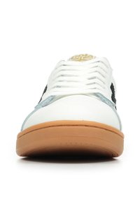 Sneaker bianco con un design nero sui lati, accenti blu chiaro, lacci bianchi e suola in gomma color pelle. Logo dorato sulla linguetta.