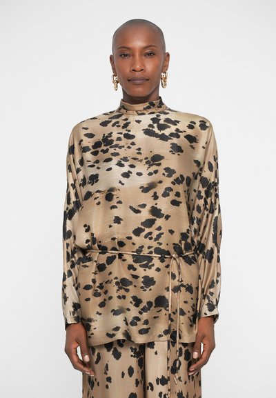 Bluză din mătase cu imprimeu de leopard, cu guler înalt, mâneci lungi și o curea ajustabilă la talie. Paleta de culori este formată din bej și negru.
