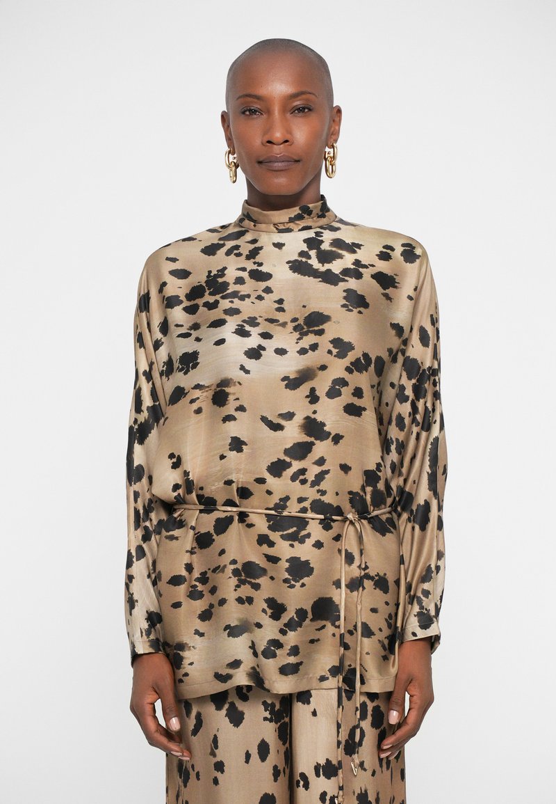 Leopard print blouse in silk with a high collar, long sleeves, and an adjustable tie at the waist. Color palette features beige and black.