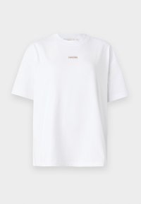 Hvit bomulls t-skjorte med korte ermer, rund hals, og en liten Calvin Klein-logo i et rektangulært merke på forsiden. Enkel design.