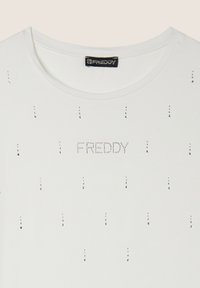 Camiseta blanca de manga corta con escote redondo, adornos plateados en forma de puntos y la palabra "FREDDY" en strass en el pecho.