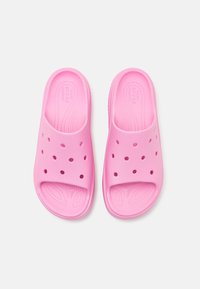 Sandales de bain roses en matériau doux, avec un design perforé et une structure à bout ouvert. Semelles texturées offrant adhérence et confort.